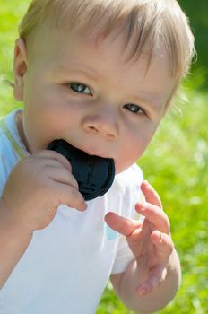 Cute baby boy holding lens cover on his mouth, outdoor