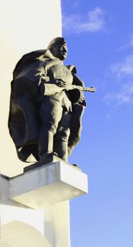 The monument to the soldier on a high pedestal on the background of blue sky