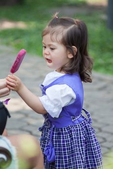 Adorable little cute girl taking icecream from her mother's hand