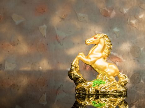 golden horse statue on glass and wood background