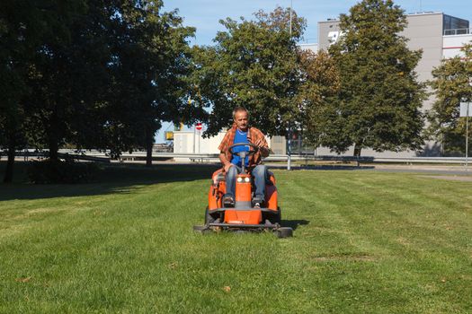 man driving a lawn mower in the city park