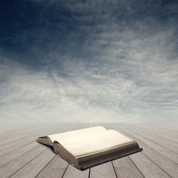 Old open book on wooden planks with blank pages and sky on background.