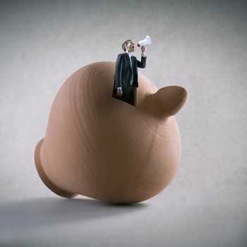 Businessman yelling through megaphone emerging from a clay coin bank.