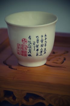 Cup with Chinese symbols, white background and wooden tray