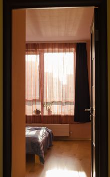 bedroom view of bed angle window with curtains illuminated by sunlight