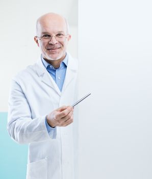 Senior doctor holding a big white sign and pointing with a pen, blank copy space.