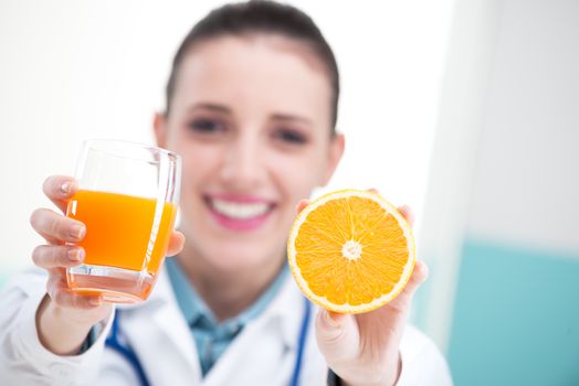 Female Nurse or Doctor. holding an orange and a glass of orange juice.