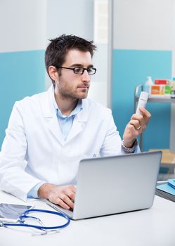 Young doctor thinking and examining prescription medicines.