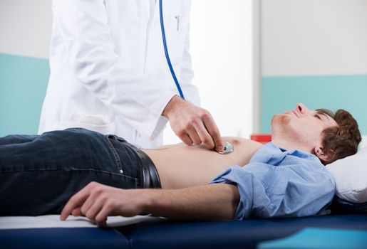 Doctor examining patient's heartbeat  with a stethoscope
