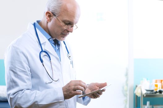 Senior doctor working with a tablet at the hospital.