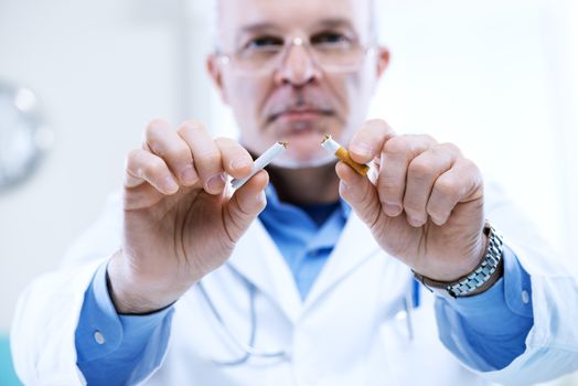 Senior doctor breaking a cigarette, stop smoking concept.