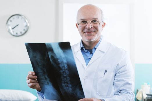 Male senior doctor looking at x-ray images of human spine.