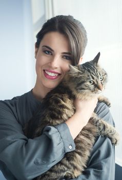 Beautiful woman smiling and holding a cute long hair cat.