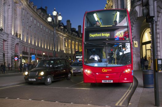 LONDON, UK – APRIL 16, 2014: London transport, Black taxi cab and red double-decker bus at Piccadilly Circus.