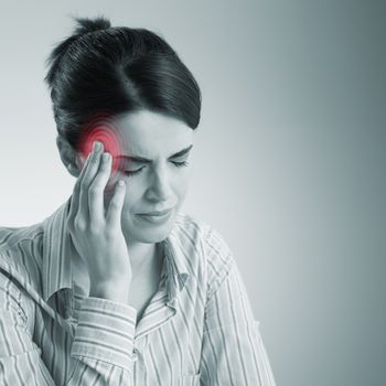 Young woman with headache touching her temples.