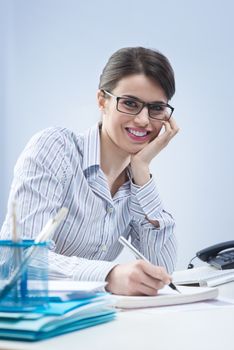 Young attractive businesswoman writing down notes and smiling.