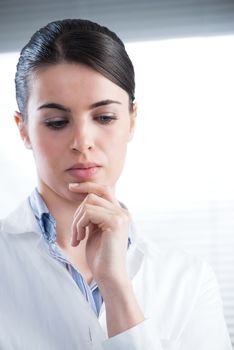 Attractive female researcher thinking with hand on chin.
