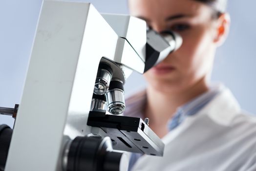 Female researcher analyzing samples with microscope in the laboratory.