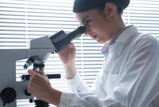 Female researcher analyzing samples with microscope in the laboratory.