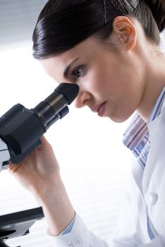 Young female researcher using microscope in the laboratory close up.