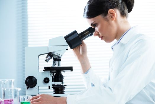 Female researcher analyzing samples with microscope in the laboratory.