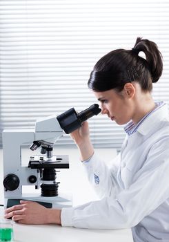 Female researcher analyzing samples with microscope in the laboratory.