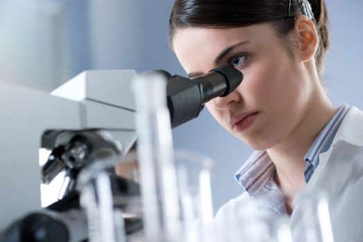 Female researcher analyzing samples with microscope in the laboratory.