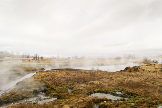 iceland hot springs with mist clouds and brown grass