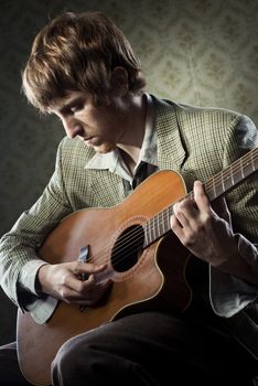 Vintage guy playing acoustic guitar and singing on retro wallpaper.