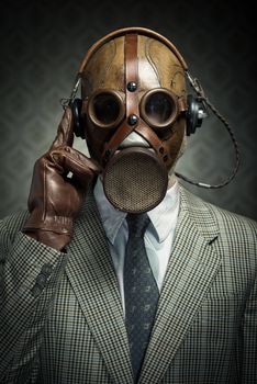Man wearing vintage gas mask and headphones listening to music.