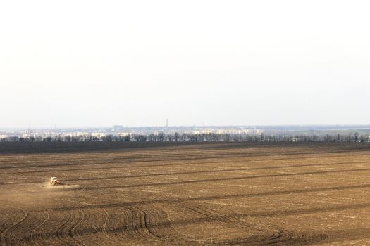 landscape spring plowed field on a background of city