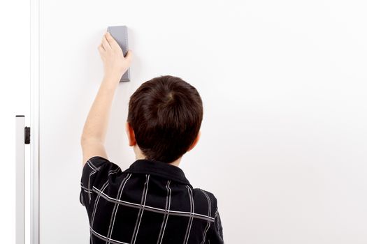 young boy student in a classroom erasing white board
