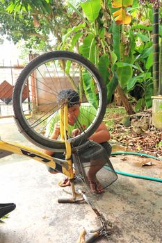 Boy repairs bicycle wheel with a wrench