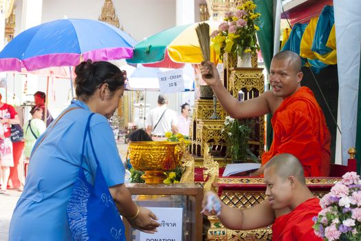 Unidentified monk pouring a holy water to people for a good luck in Songkran festival tradition of thailand. Photo: Amnarj2006/ yaymicro.com