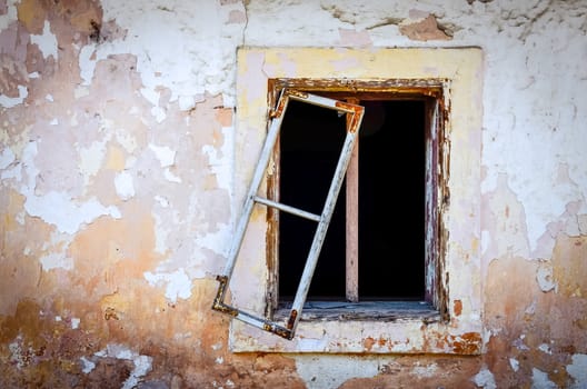 Detail of old damaged window on textured cracked wall