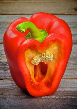 Cut into Half Raw Red Bell Pepper and Seeds isolated on Wooden background