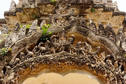 ancient complicated stucco work showing of traditional thai pattern that decorated with mirror and precious stone at temple entrance gate ,Lampang temple,Thailand