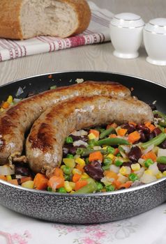 Homemade sausages with vegetables in a pan
