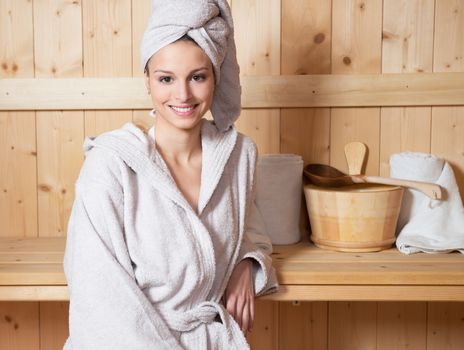 Young attractive woman smiling and relaxing in sauna at spa.