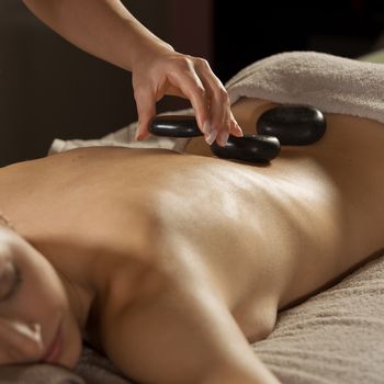 Attractive woman receiving a relaxing hot stone massage on her back.