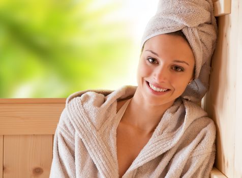 Young attractive woman smiling and relaxing in sauna at spa.