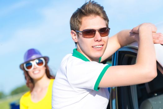 young man in sunglasses standing next to the car, the summer road trip
