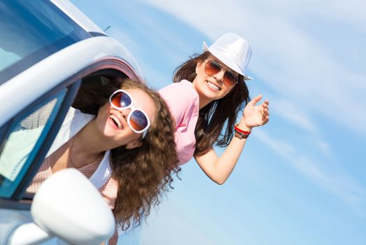 young attractive woman in sunglasses got out of the car window and laugh