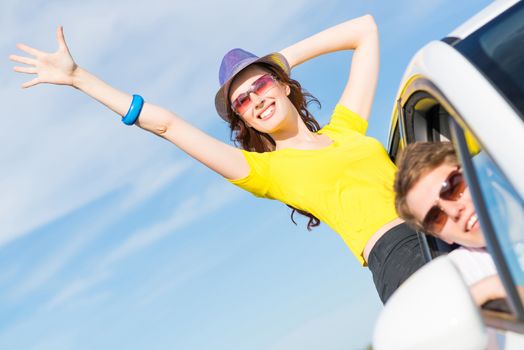 young attractive woman in sunglasses got out of the car window and laugh