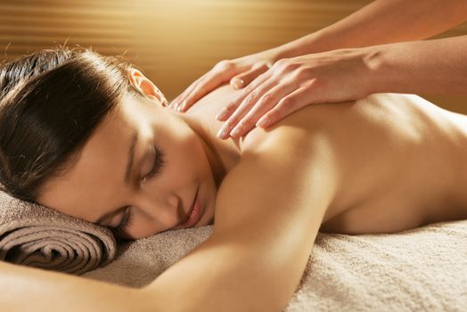 Beautiful woman receiving a relaxing back massage at spa.