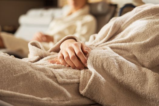 Women in bathrobe relaxing at spa, lying on a sofa.