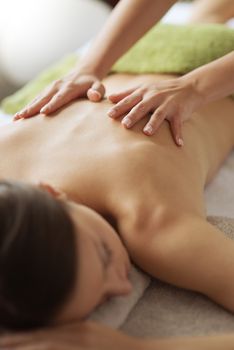 Beautiful woman receiving a relaxing back massage at spa.