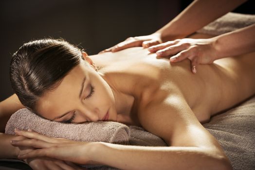 Beautiful woman receiving a relaxing back massage at spa.