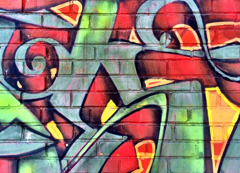 Colorful red and green graffiti detail on a brick wall.