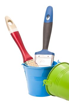 Paint brushes in green and blue tin buckets isolated on white